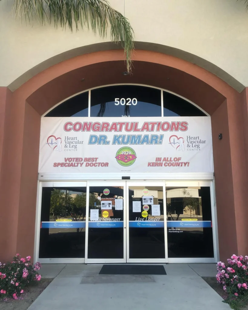 Banner congratulating Dr. Kumar for being voted best specialty doctor, displayed at the Heart Vascular and Leg Center entrance, featuring vibrant colors and promotional text.