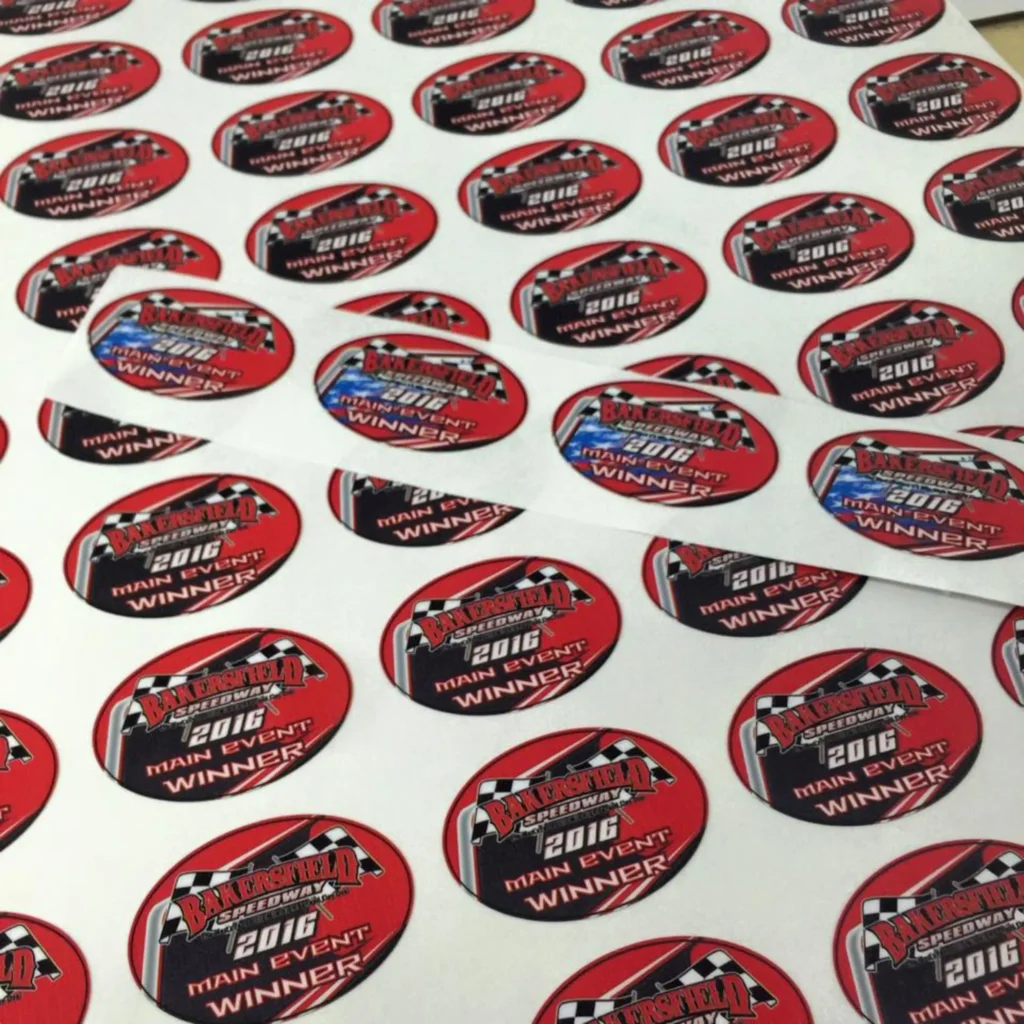 Bakersfield Speedway 2016 Main Event Winner decals on a sheet, showcasing vibrant red and black designs with checkered patterns, highlighting custom decal craftsmanship.
