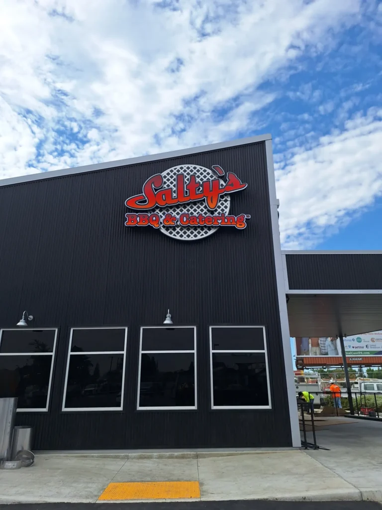 Close-up of the Salty's BBQ & Catering 3D channel letter logo sign on a dark metal storefront in Bakersfield, CA