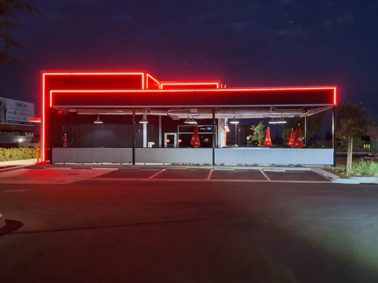 Front view of the Salty's BBQ & Catering covered patio framed by red LED accent lighting at night in Bakersfield, CA